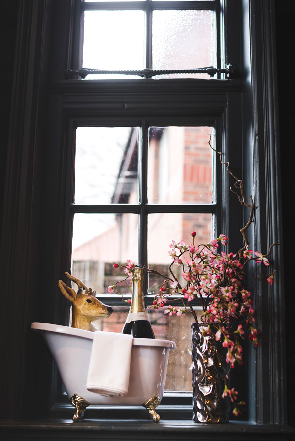 A bottle of champagne chilling in a roll-top bath on the windowsill, framed by
faux blossom and a little stag — festive touches at The Whippet Inn