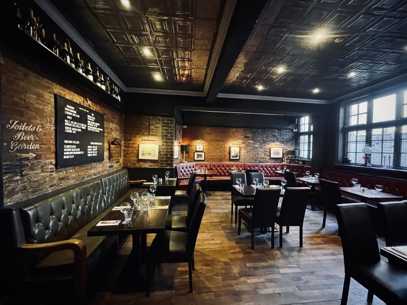 Red leather banquettes and set tables beneath the pressed-tin ceiling — one of
the characterful spaces for private hire