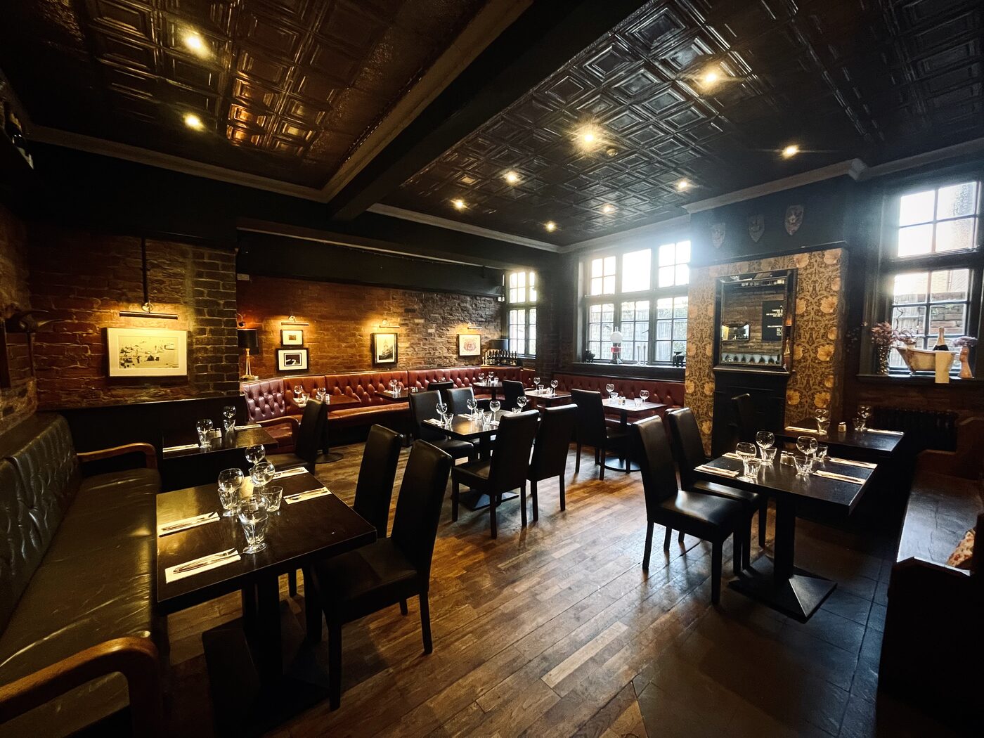 The main dining room at The Whippet Inn — laid tables, leather banquettes,
bare Victorian brick and a pressed-tin ceiling
